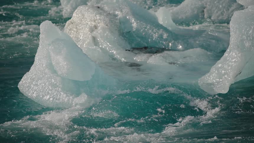Small and medium pieces of ice melting at the ocean under the sunlight outdoors during day time