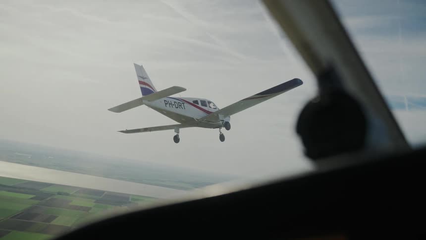 Singleengine aircraft flies with landing gear down over a rural landscape
