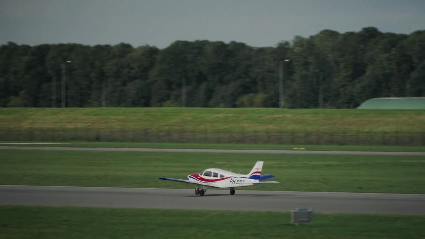 Singleengine aircraft taxiing on runway surrounded by flags and grassy area