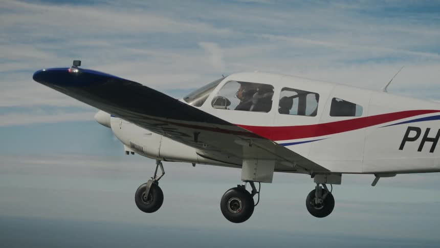 Archer aircraft flying over coastal area with greenery and buildings