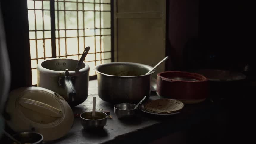 Used cooking pots and utensils sit on a dimly lit kitchen counter near a window