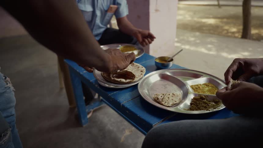 People share a meal with flatbreads and plated dishes on a blue table
