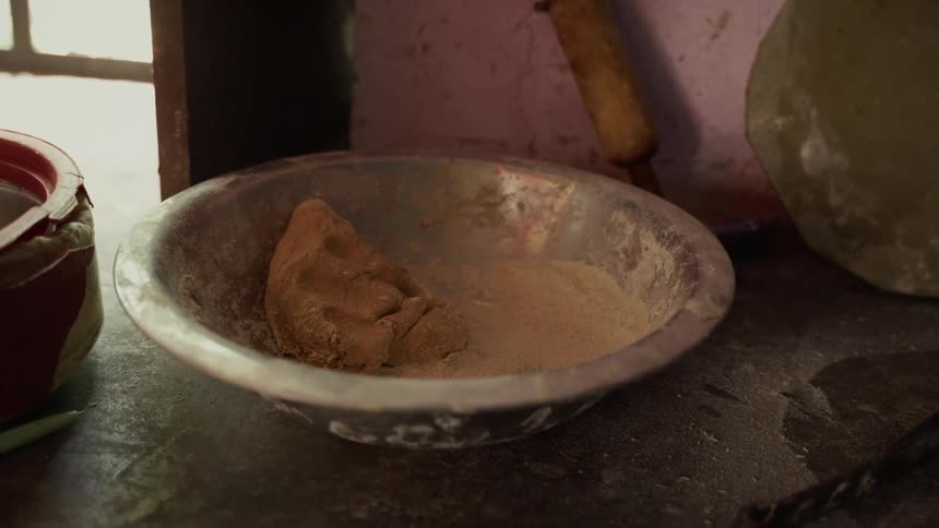 A pan filled with flour place on the floor inside a kitchen at midday