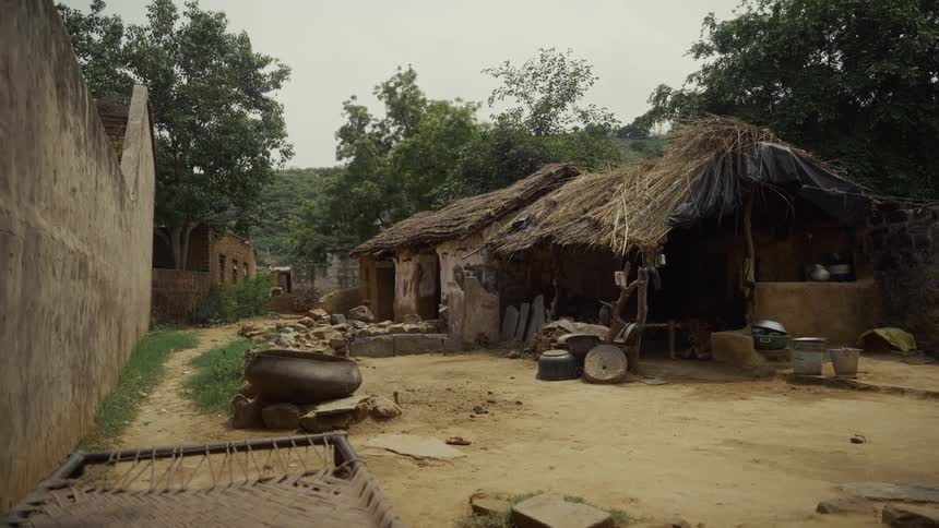 A hut stands in a village setting at midday within a rural environment of a developing nation
