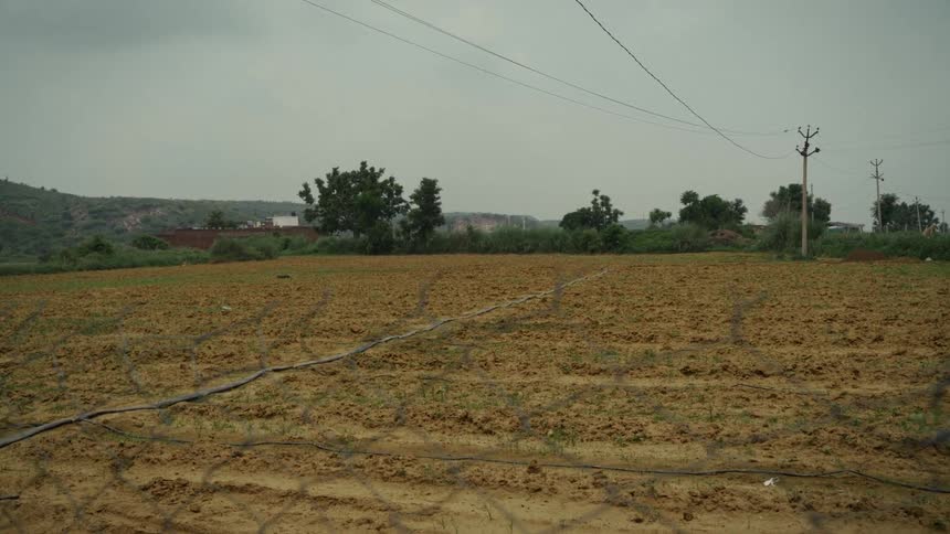 Utility wires stretch across open rural land with mountains in the distance