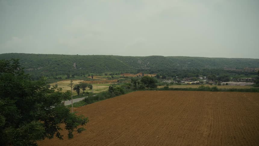 Plowed fields stretch toward green hills under an overcast sky