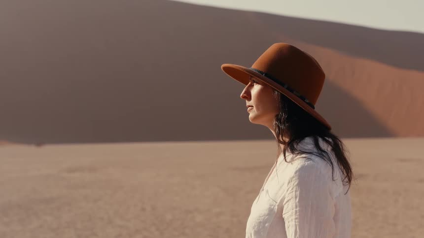 Person wearing brown hat and white shirt in desert landscape
