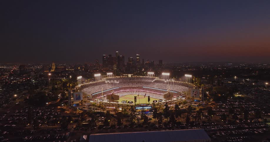 Dodger stadium lit up during nighttime game with stands packed with spectators