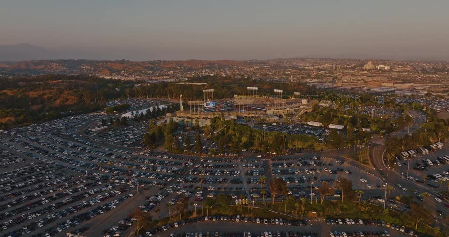 Vehicles fill the parking lots surrounding a stadium on a foggy day