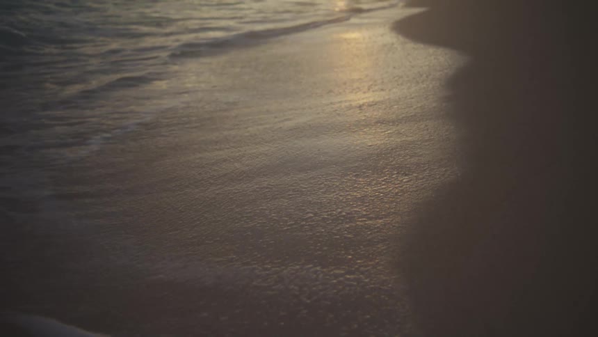 Wet sand reflecting golden light along the shoreline at sunset
