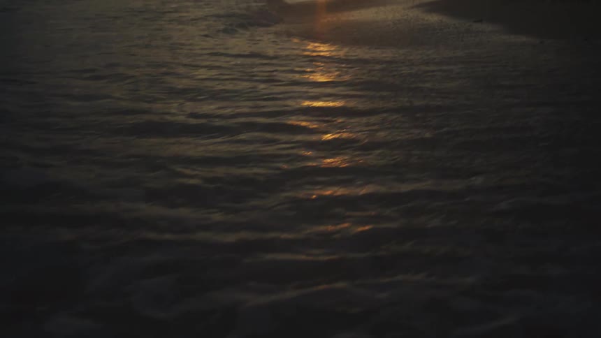 Sun reflected on the sea during sunset at a calm beach
