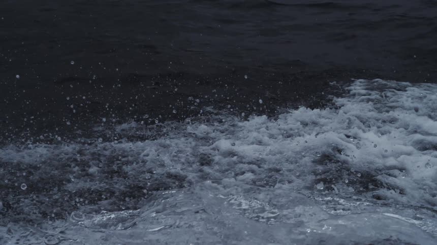 Choppy seawater with white foam contrasting against darker calmer background