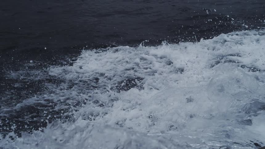 Agitated water with white foam contrasting against dark sea in the background