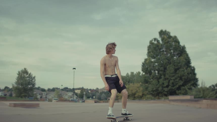 Male teenage skateboarder jumps down outdoor steps on a summer day