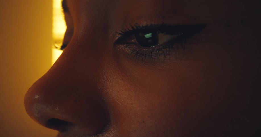 Woman reads on a computer as her eye reflects the computer screen