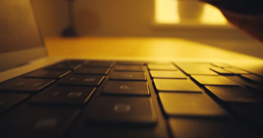 A woman is typing indoors on a laptop keyboard