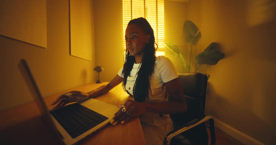 A woman sitting at a desk opens up her laptop computer