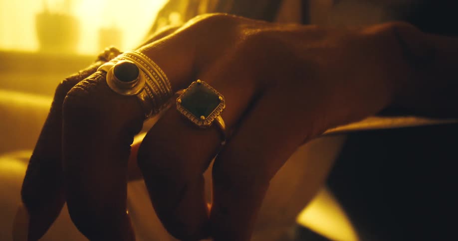 Hand with ornate rings in relaxed position under golden light and blurred background