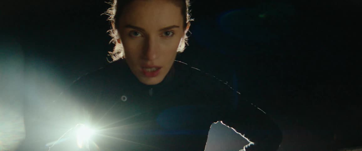Woman adjusting her watch and starting to run at night