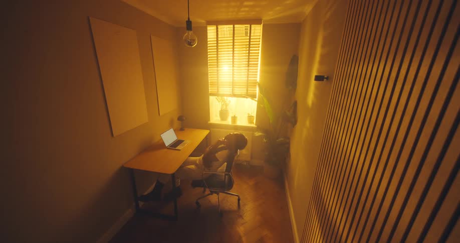 View from above as a woman sitting at a table opens her laptop computer and types on the keyboard and moves back in her chair thinking