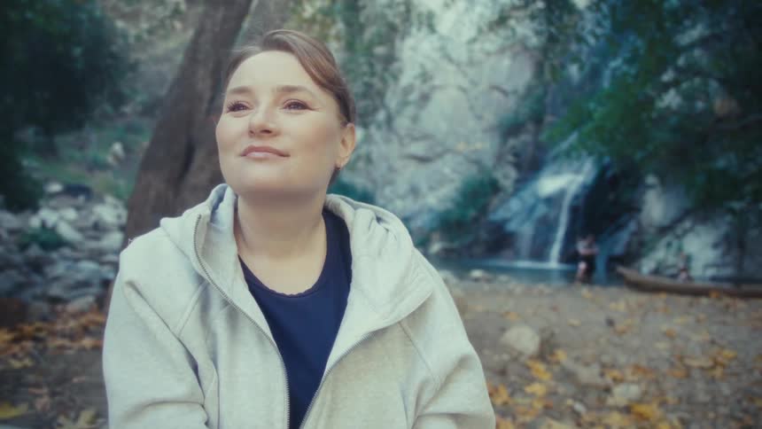 A woman sitting outdoors near a waterfall