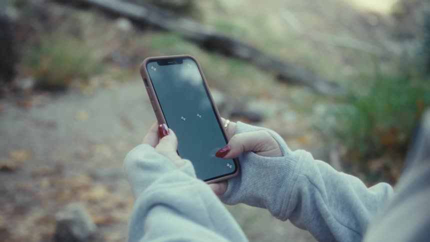 Closeup of hands holding and tapping a smartphone outdoors