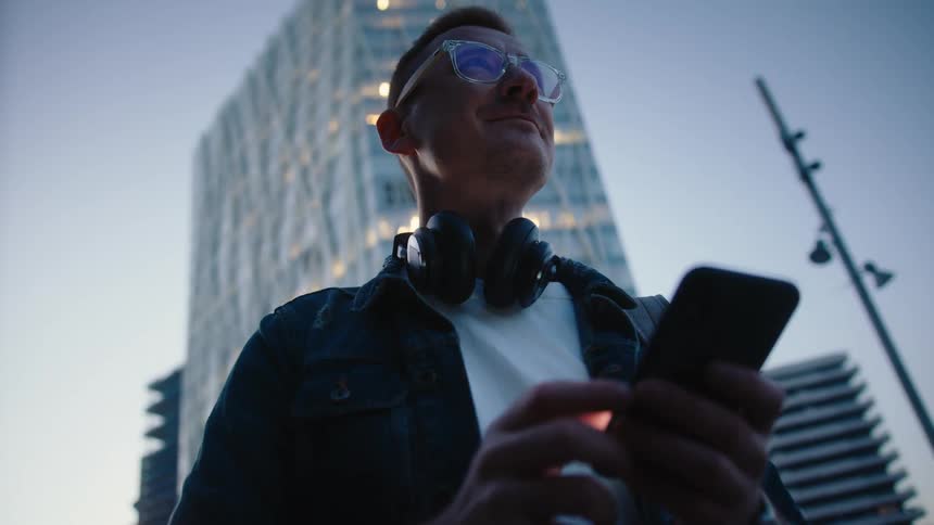The man is using his cell phone by the building