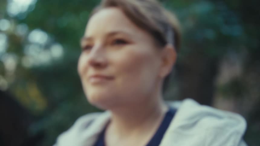 Woman stands outside holding her phone and smiles