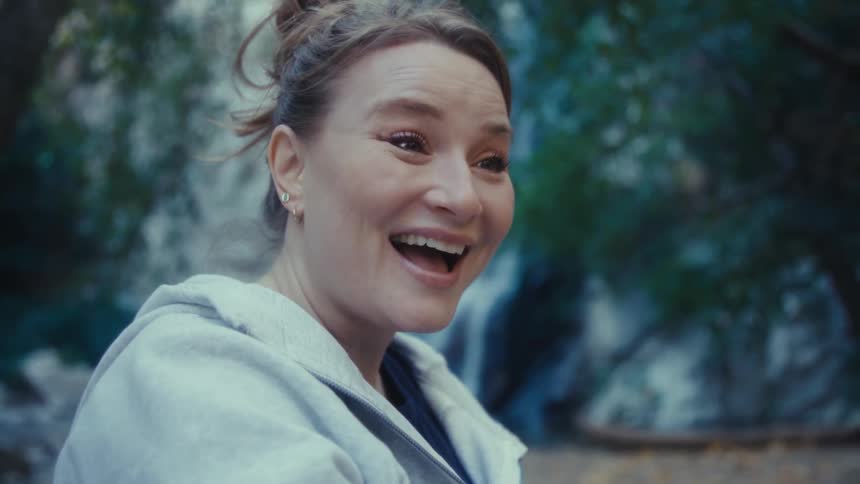 Woman holds out her phone as she smiles and laughs in conversation