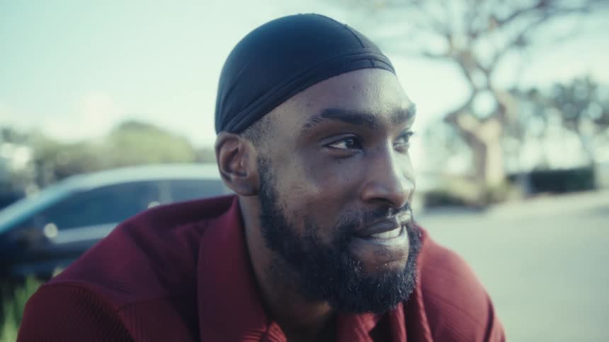 Man wearing black durag and red shirt in urban setting
