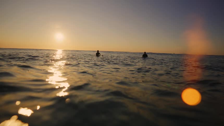 Silhouette of two people in the middle of the ocean outdoors during dusk or dawn