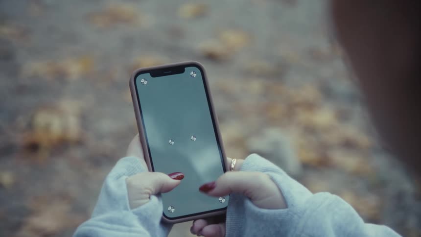 Woman holds her phone with both hands texting with her thumbs