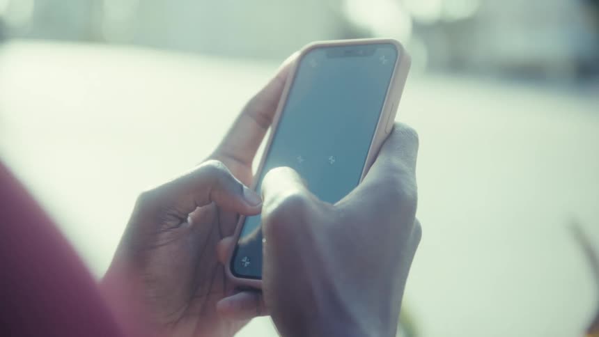 Woman holds her phone with both hands as she moves her thumb across the screen