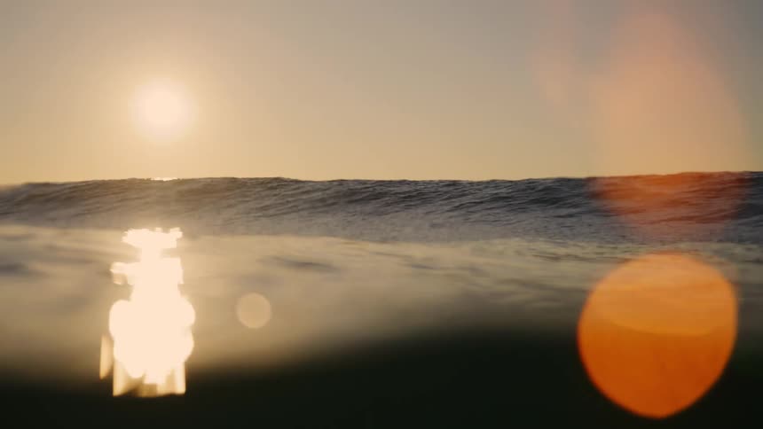 Golden sunrise over ocean waves with sunlight streaming across the water