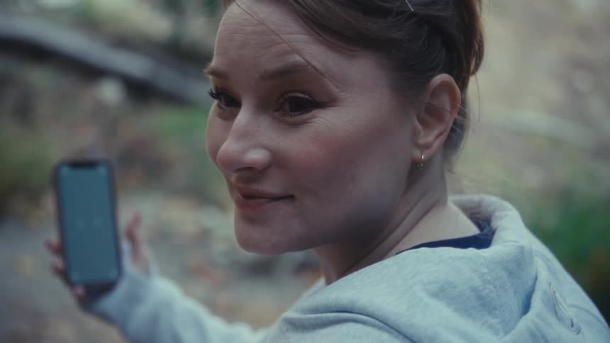 Smiling woman outdoors holding phone