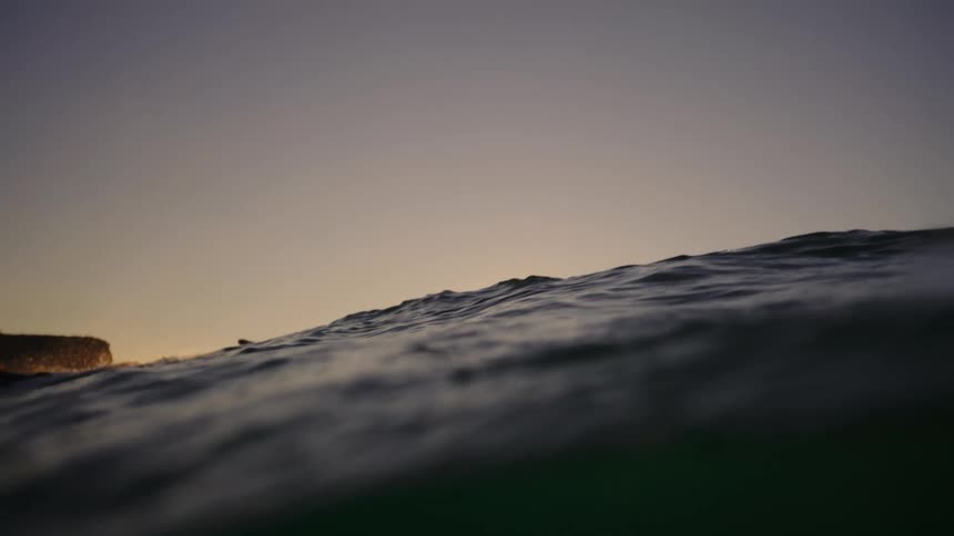 Two men are surfing as the sun slowly rises