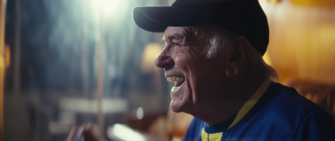 An elderly man is cheering holding the american flag while watching tv