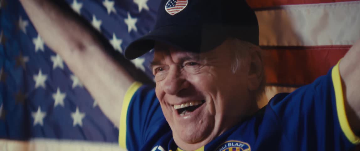 Smiling elderly man wearing cap in front of us flag