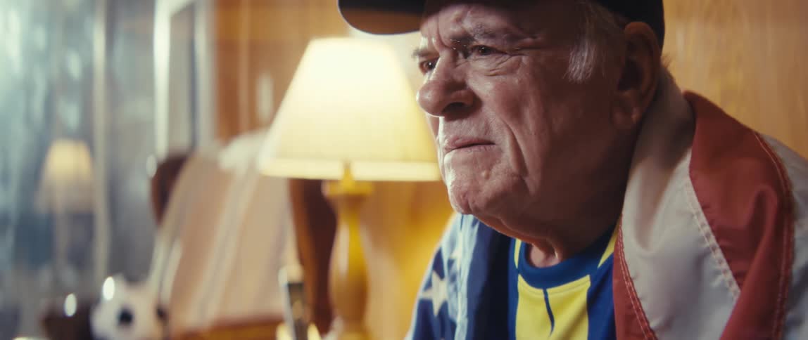 An elderly man nervously reacts to watching sports on tv
