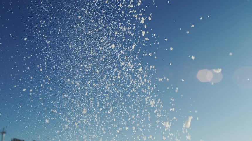 Fast falling snowfall onto a snow covered hill under a bright blue sky
