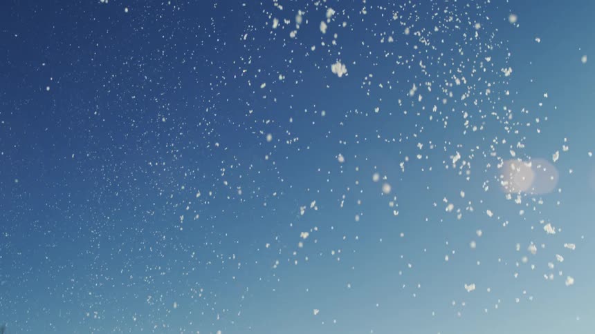 Snow falls and sparkles in the sunlight under a clear sky