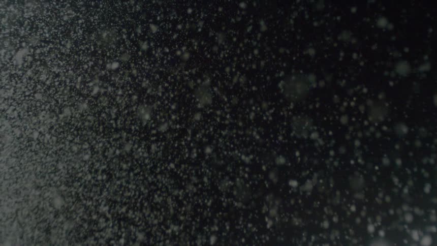 Snow falling in dark setting with illuminated particles
