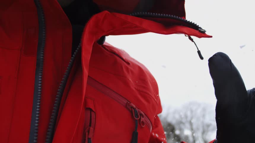 Person in red snow jacket unzipping the front