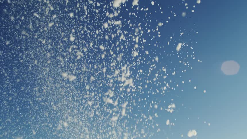 Snow falls and sparkles in the sunlight under a clear sky