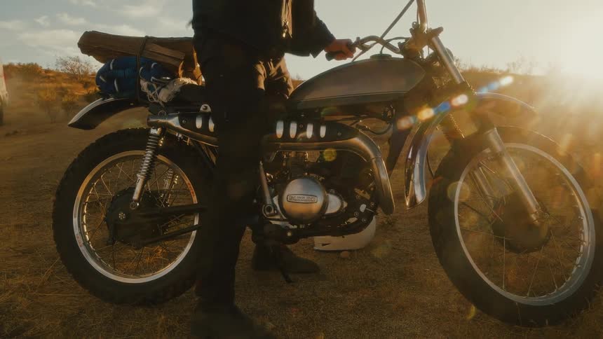 Rider steadies the motorcycle on sunlit ground