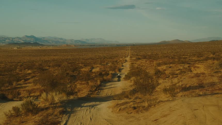 A person riding a dirt bike down a trail during the day