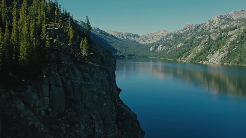 Calm lake reflecting rocky mountains and forests in highaltitude setting
