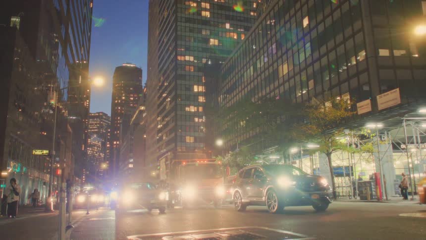 Heavy traffic lights up the street between tall buildings at dusk