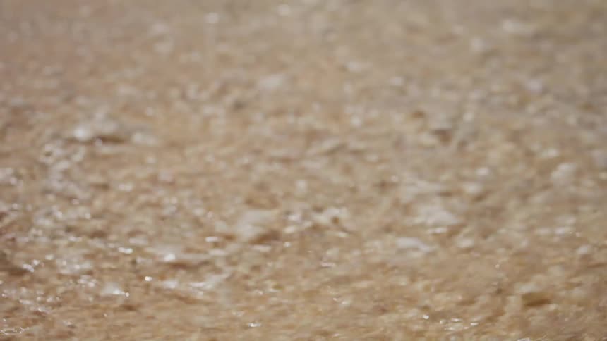 White foam from waves slides over pebbled sand at the oceans edge