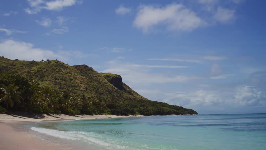 Blue water hits the sand of the tropical island
